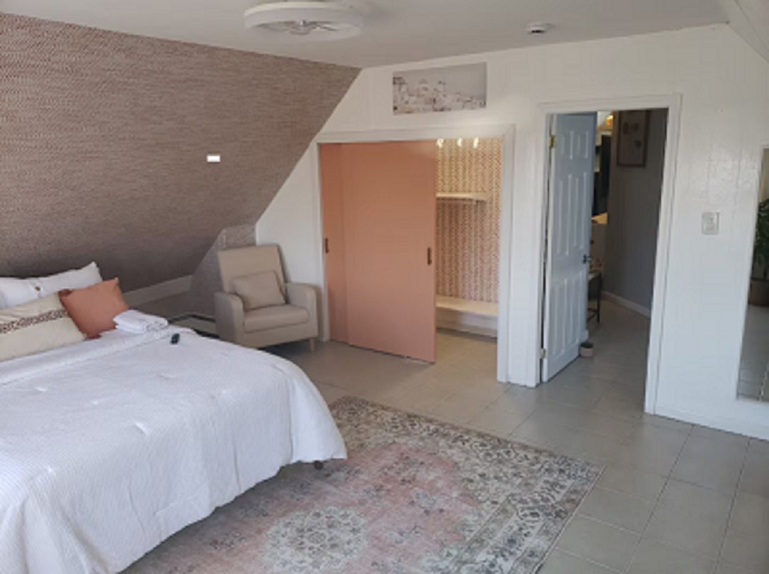 The main bedroom, with a sloped ceiling, armchair and sliding closet
